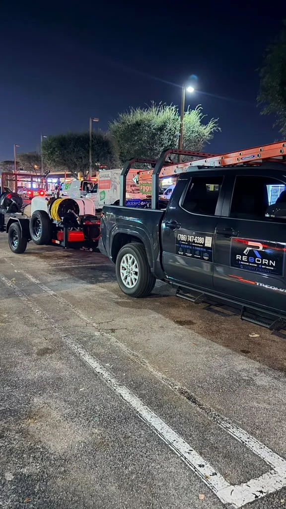 Branded REBORN truck and cleaning trailer at a shopping plaza at night